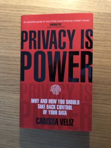 Hardback book on desk. Privacy is Power by Carissa Veliz. A book about personal data in technology. Red cover with black title.